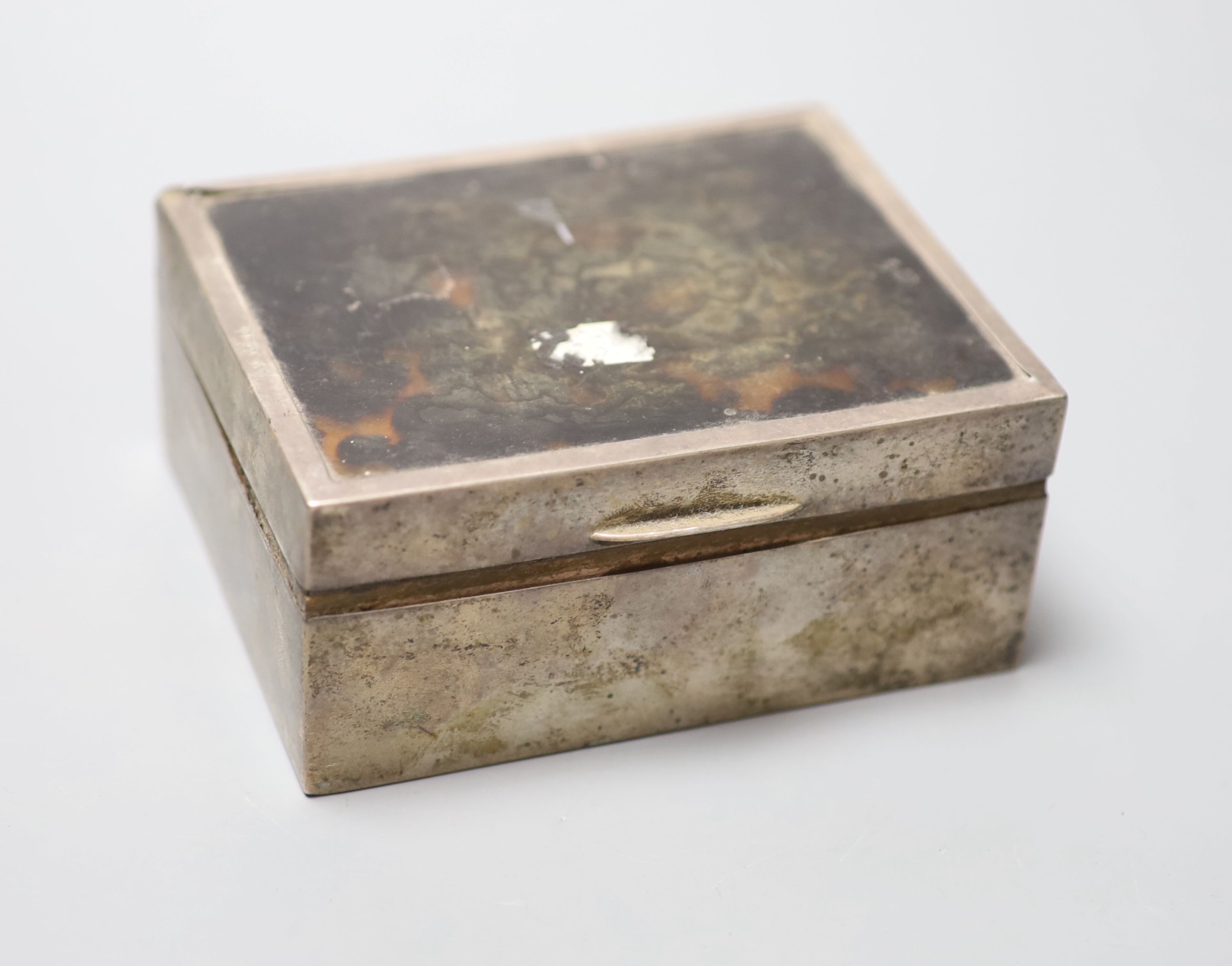 A 1920s silver and tortoiseshell mounted cigarette box, containing a fitted matched silver ashtray and mounted matchbox sleeve,